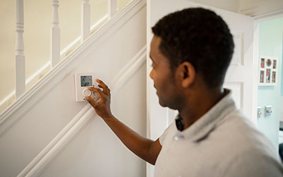 Man adjusts the thermostat in his home