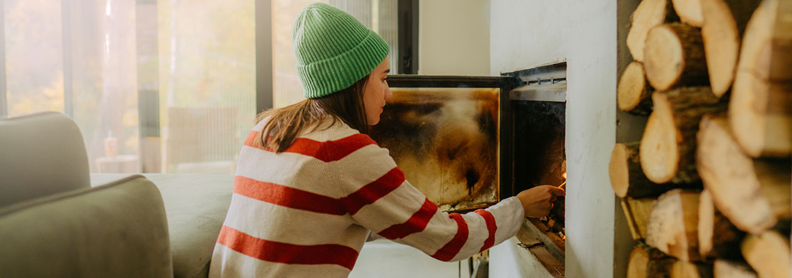 woman-adding-wood-to-fireplace-1140x400