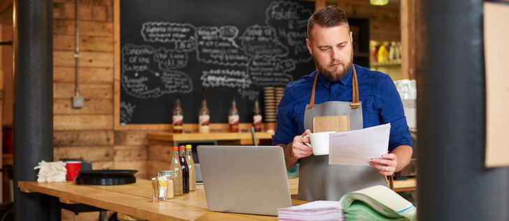 Coffee shop owner reviewing business savings account documents