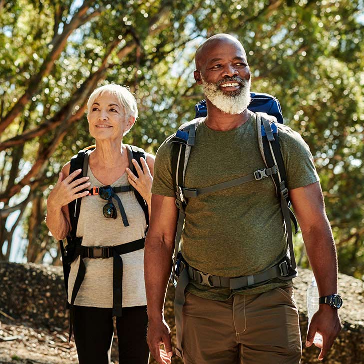 Mature couple hiking through woods