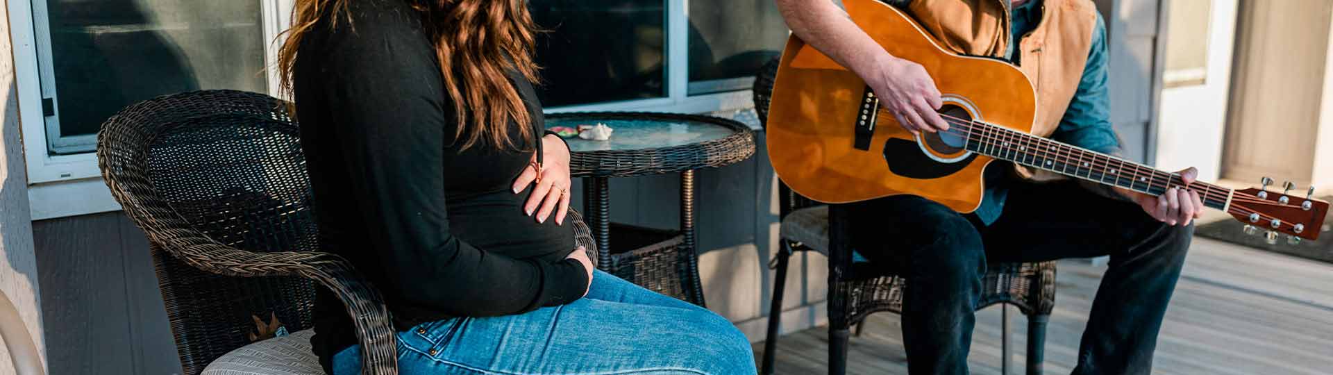 Man playing guitar on the front porch while sitting with a woman